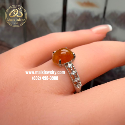 Two Silver Jadeite Jade Rings featuring a translucent green Type A Burmese jadeite cabochon and a vibrant honey-orange jadeite cabochon on a white marble display.