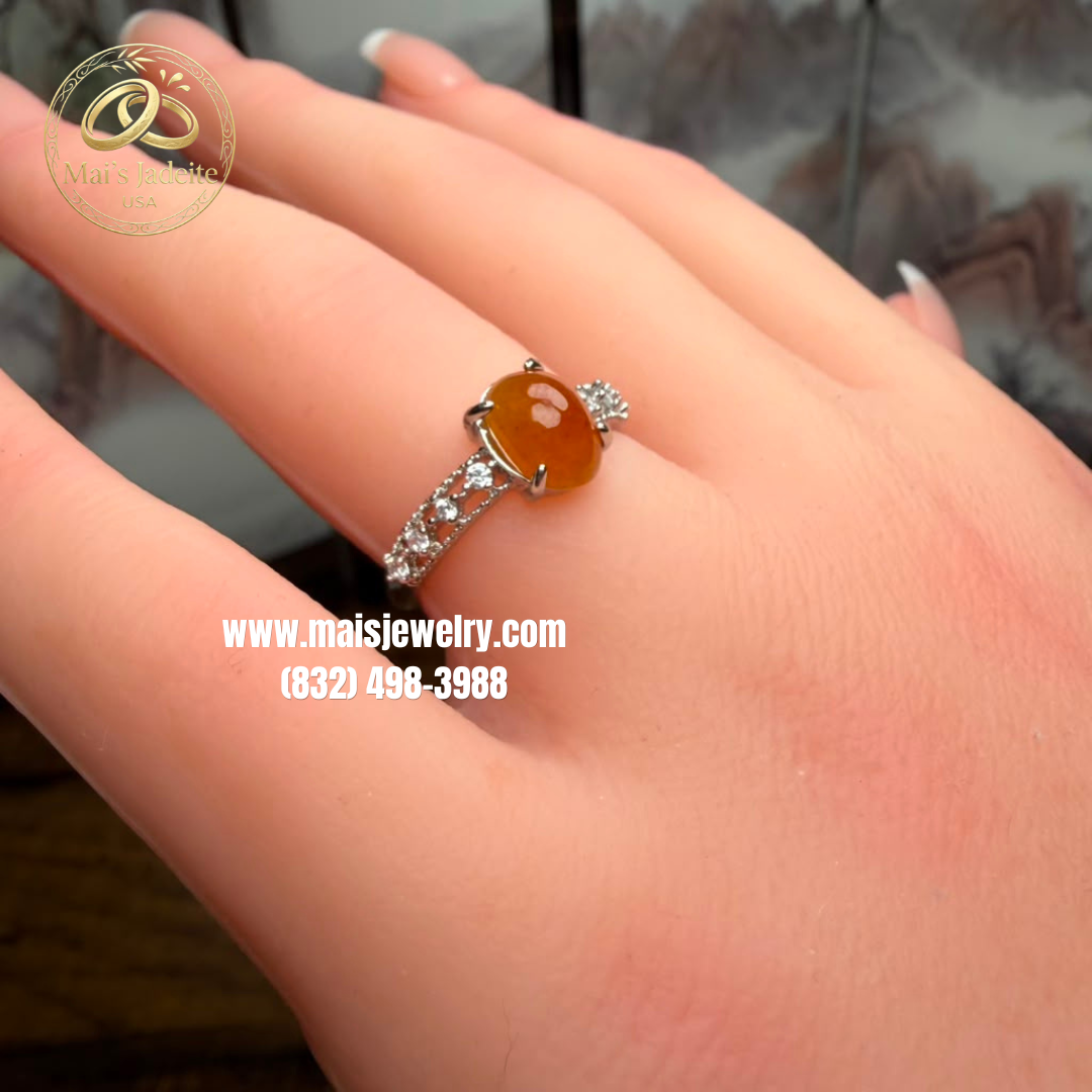 Two Silver Jadeite Jade Rings featuring a translucent green Type A Burmese jadeite cabochon and a vibrant honey-orange jadeite cabochon on a white marble display.