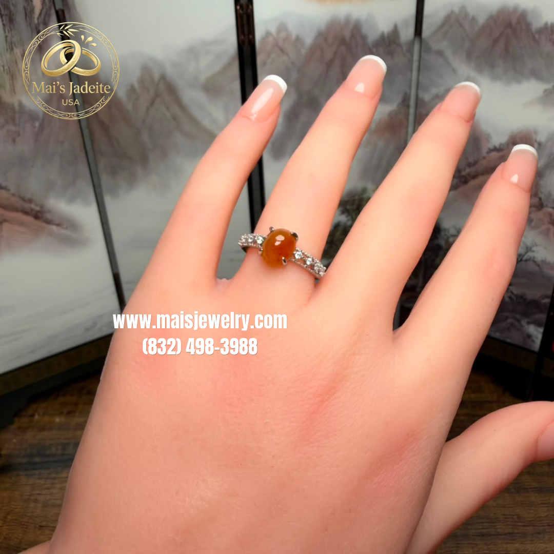 Two Silver Jadeite Jade Rings featuring a translucent green Type A Burmese jadeite cabochon and a vibrant honey-orange jadeite cabochon on a white marble display.