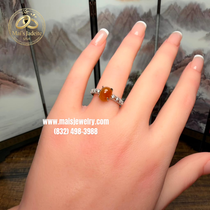 Two Silver Jadeite Jade Rings featuring a translucent green Type A Burmese jadeite cabochon and a vibrant honey-orange jadeite cabochon on a white marble display.